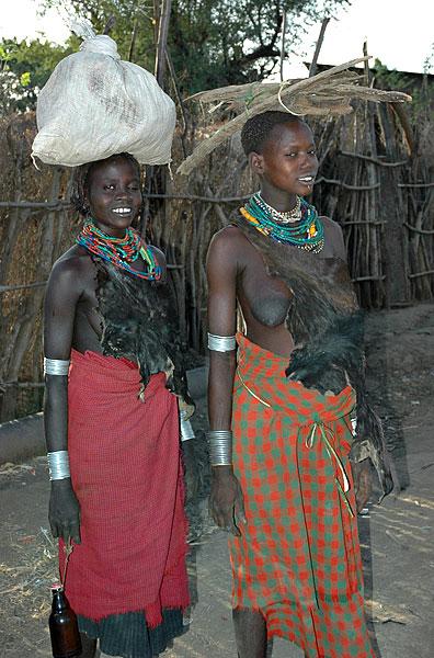 Galeb women in Omorate - wearing traditional goat skin and carrying loads on their head.