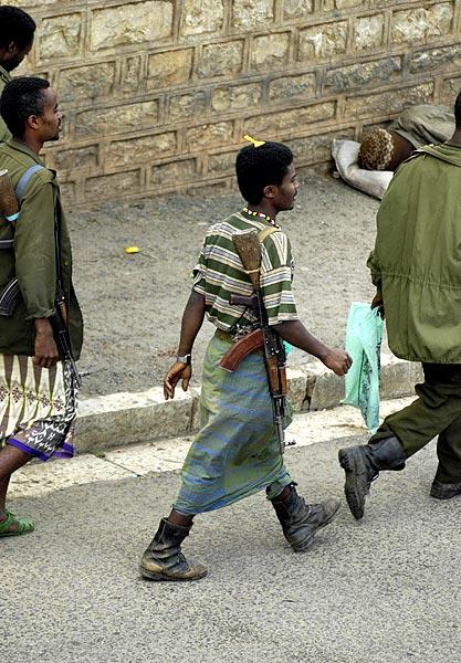 Odd fashion in Harrar - a machine gun, a skirt, boots, a watch on backwards, and a comb in the hair.